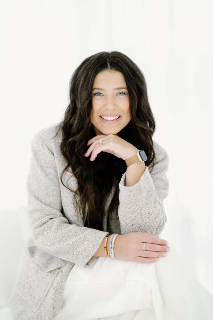 Smiling woman in a light-colored jacket.